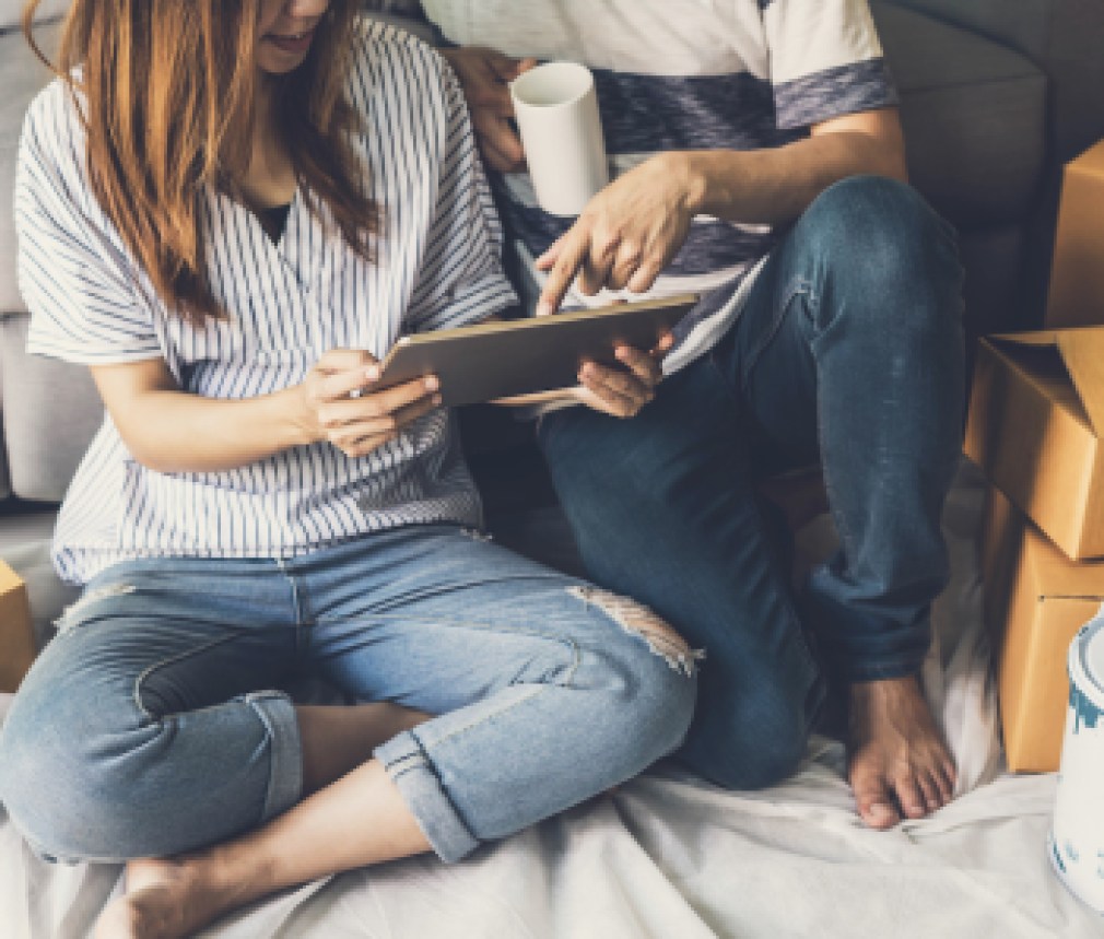 Young happy couple moving in new home, sitting and relaxing on the floor