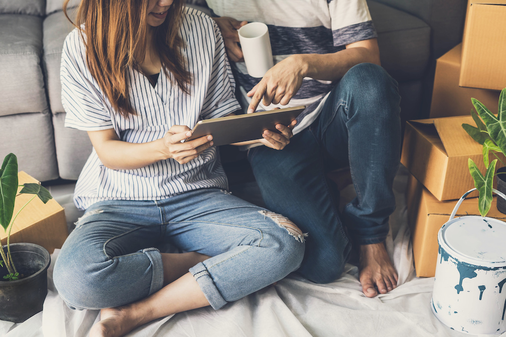 Young happy couple moving in new home, sitting and relaxing on the floor