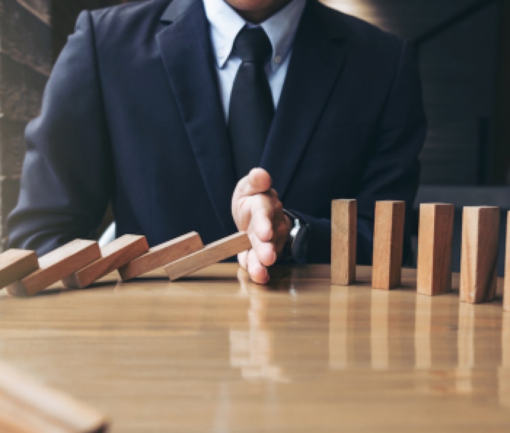 Close up of businessman hand Stopping Falling wooden Dominoes effect from continuous toppled or risk, strategy and successful intervention concept for business