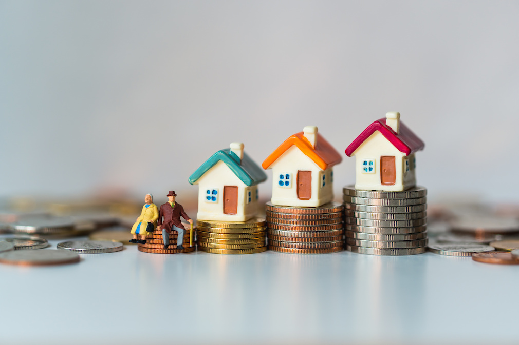 Miniature elderly people sitting on stack coins and mini house using as job retirement, business and insurance concept