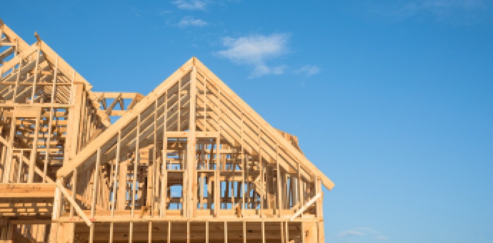 Close-up of gables roof on stick built home under construction and blue sky in Humble, Texas, USA. New build roof with wooden truss, post and beam framework. Timber frame house, real estate. Panorama