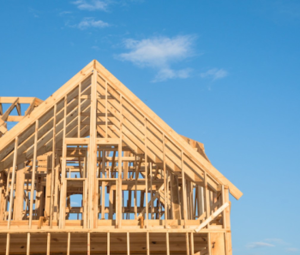 Close-up of gables roof on stick built home under construction and blue sky in Humble, Texas, USA. New build roof with wooden truss, post and beam framework. Timber frame house, real estate. Panorama