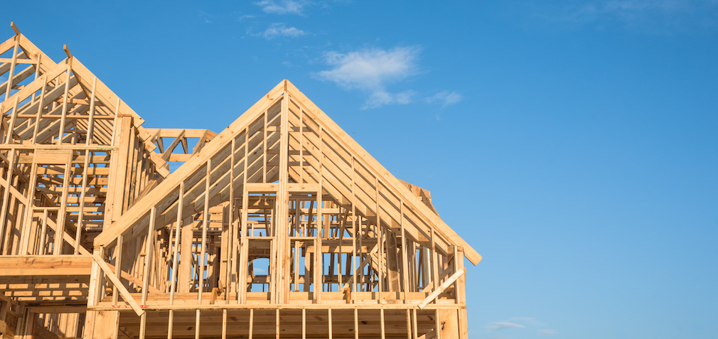 Close-up of gables roof on stick built home under construction and blue sky in Humble, Texas, USA. New build roof with wooden truss, post and beam framework. Timber frame house, real estate. Panorama