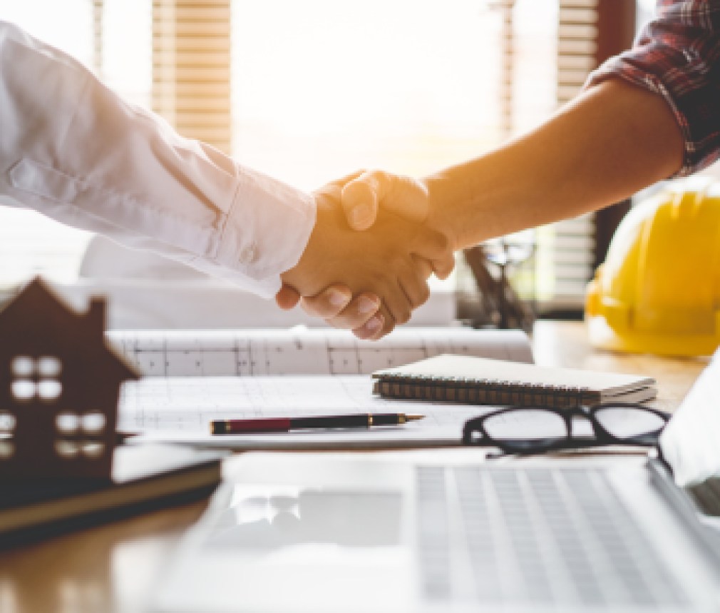 Client shaking hands with contractor after confirm blueprint to renovate house.