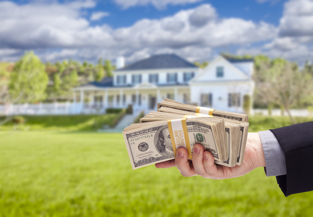 Handing Over Cash For House in Front of Beautiful New Home.