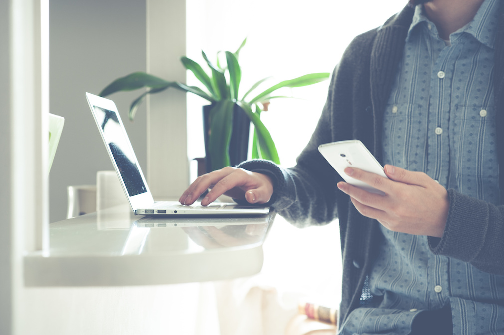 man looking at phone and laptop