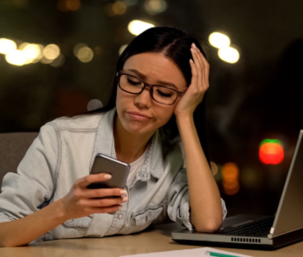 Lazy woman using cell phone at workplace, avoiding boring job, distraction