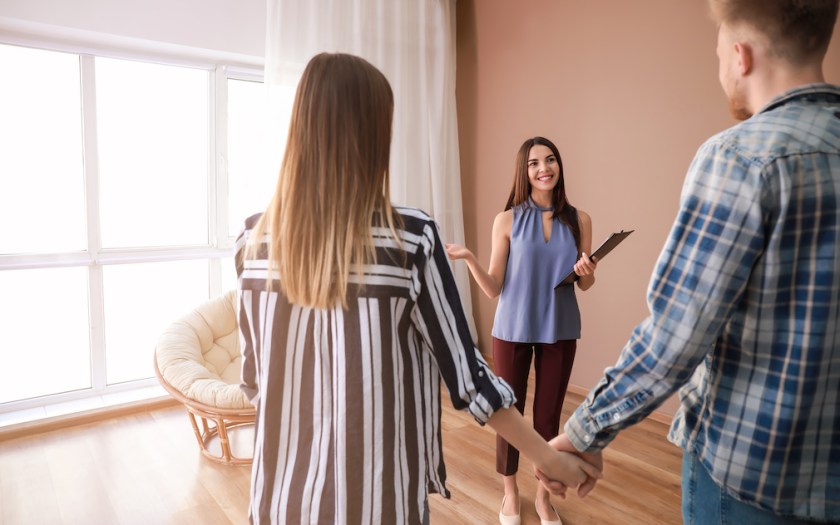 Real estate agent showing young couple a new house