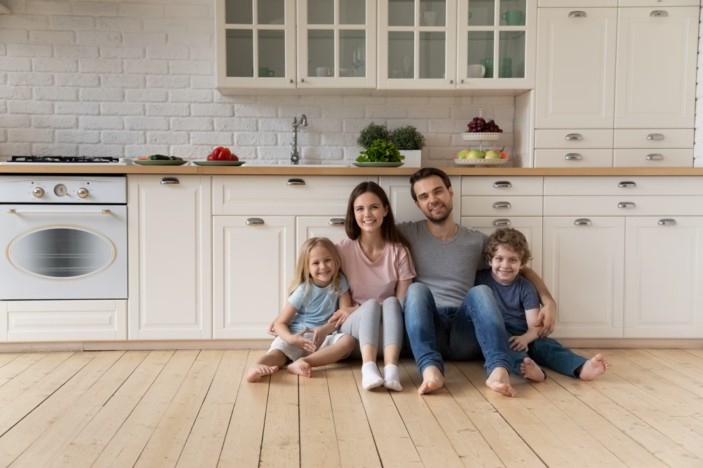 Portrait of happy family sitting on floor at kitchen.