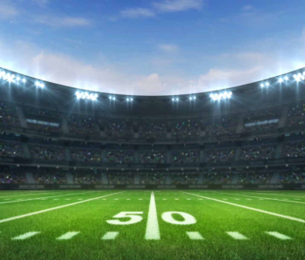 American football league stadium with white lines and fans, daytime side field view