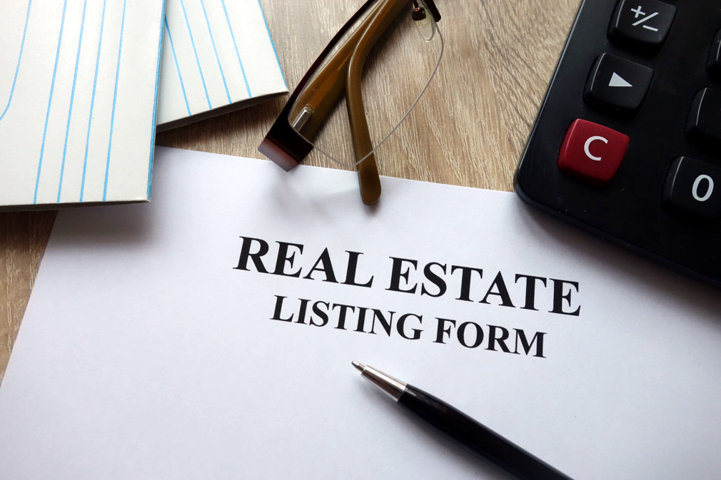 Real estate listing form with pen, calculator and glasses in office