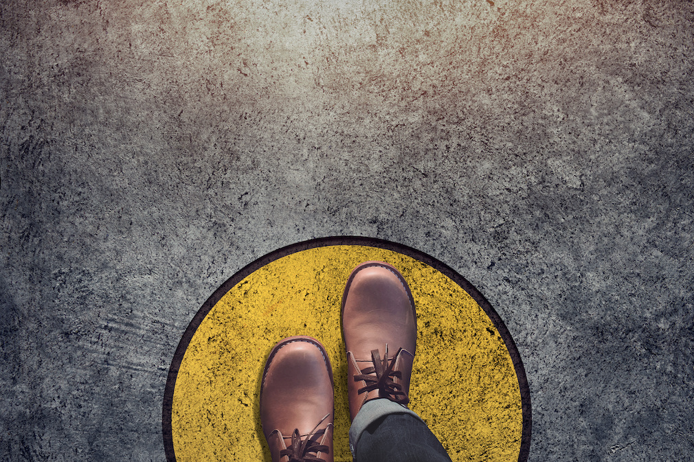 Comfort Zone concept, Male with leather shoes steps over circle line to outside bound, Top view and Dark tone, Grunge Dirty Concrete Floor as Background