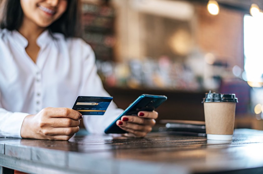 Pay for goods by credit card through a smartphone in a coffee shop.