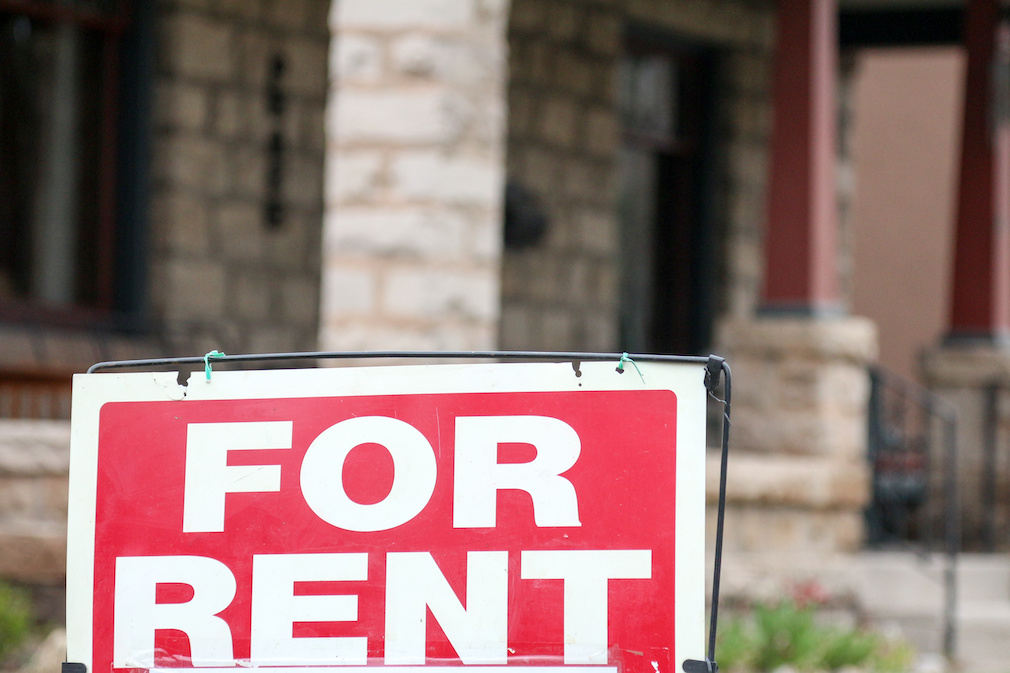 For rent sign posted in front of a blurry front porch