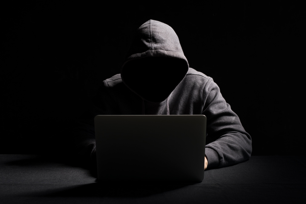 Hacker working on laptop in the dark
