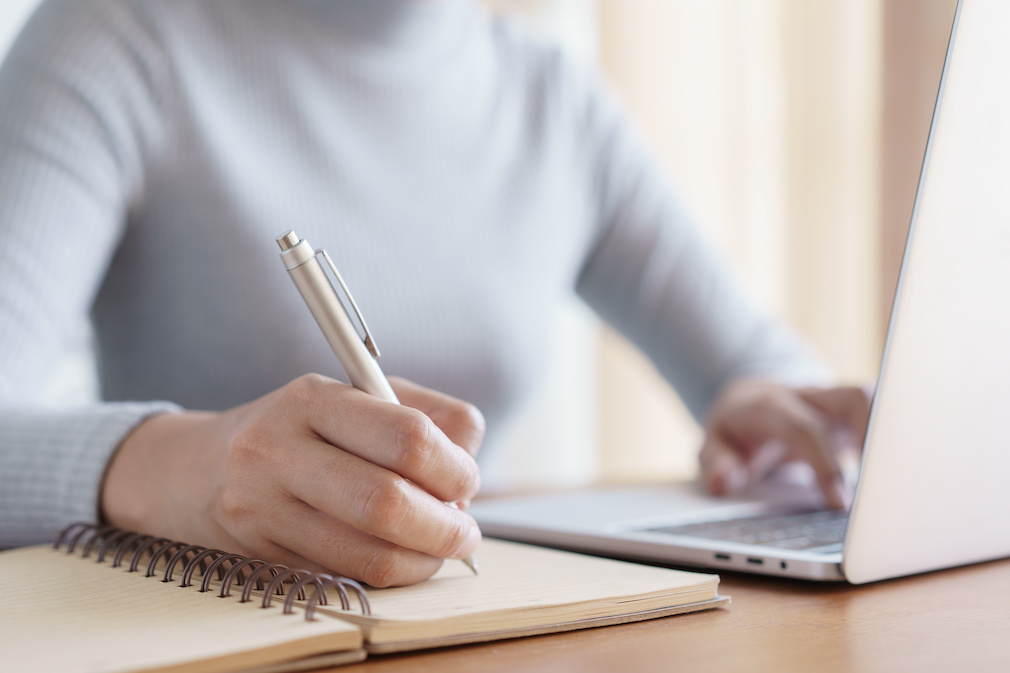 Hand of business women using laptop and write notebook while sitting working on the desk in the office