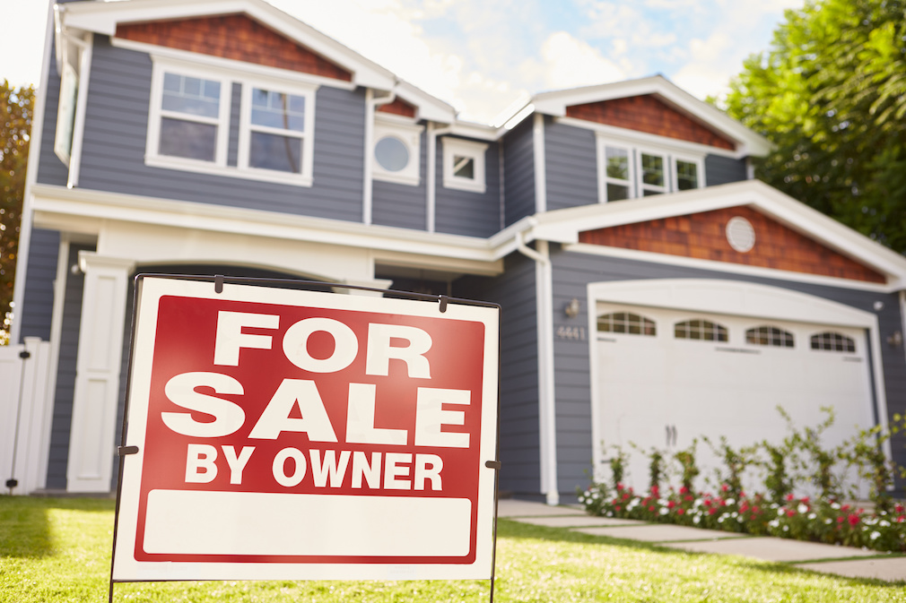 Large suburban house with ‘for sale’ sign displayed outside