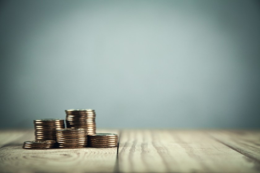 Stack of coins on wooden table.