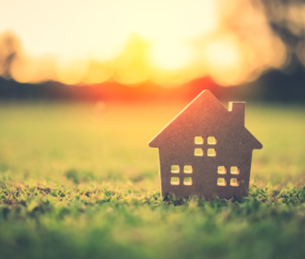 Copy space of home and life concept. Small model home on green grass with sunlight abstract background.