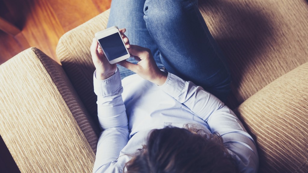 Aerial view of girl reading a phone while sitting in a couch. Vintage tone.