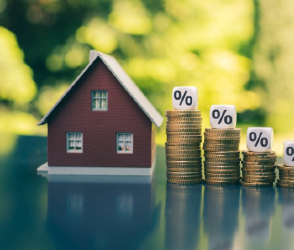 mortgage rates, Symbol for decreasing interest rates. Dice with percentage symbols on decreasing high stacks of coins next to a model house.