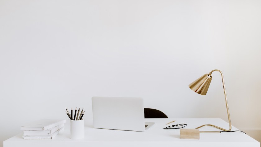 Office with laptop, lamp, notebooks. White working study cabinet. Outsourcing freelancer, blogger, boss workspace.