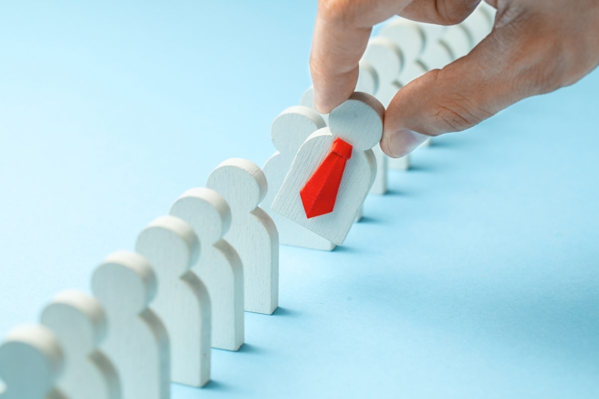 job growth depicted by a hand plucking wooden figure from a line