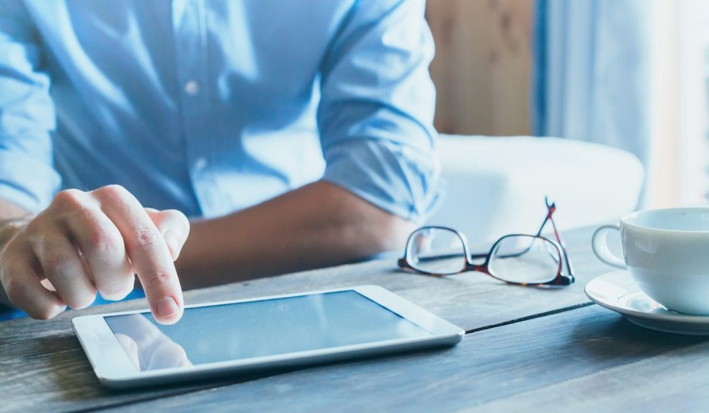 man using digital tablet computer, close up of the hand, business and technology background with copy space