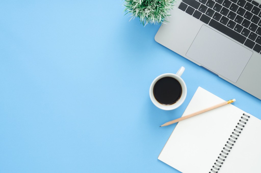 Minimal work space - Creative flat lay photo of workspace desk. Top view office desk with laptop, notebooks and coffee cup on blue color background. Top view with copy space, flat lay photography.