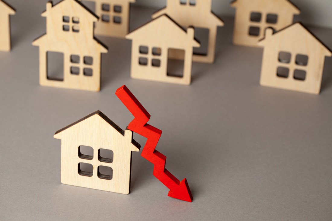 Arrow down and many houses. Falling real estate prices market. Buying and selling house
