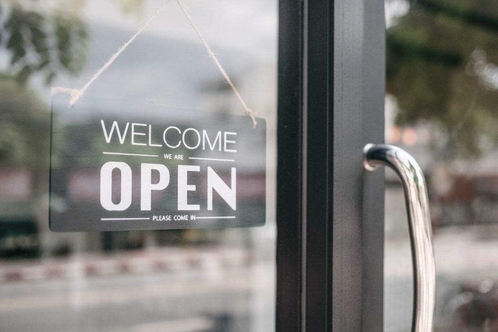 Closeup of open and welcome to store sign board at the door.