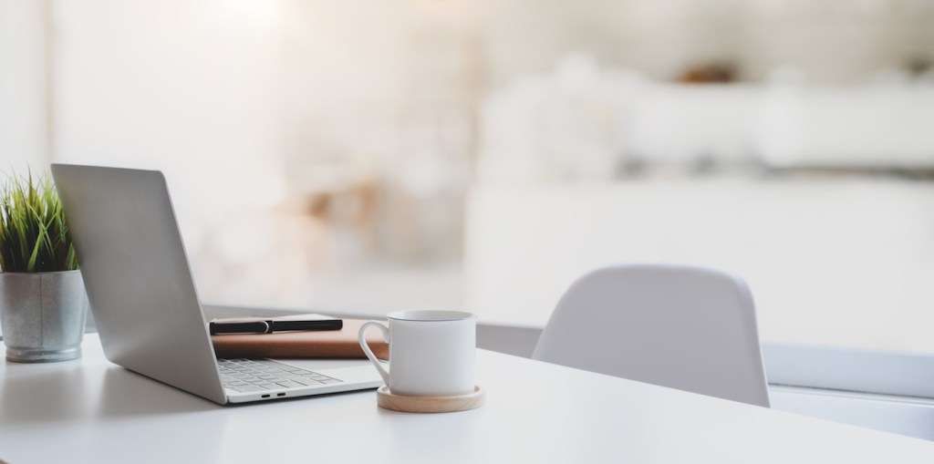 Modern workplace with laptop computer, coffee cup and office supplies