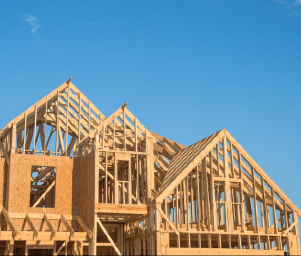 Close-up of gables roof on stick built home under construction and blue sky in Humble, Texas, USA. New build roof with wooden truss, post and beam framework. Timber frame house, real estate background