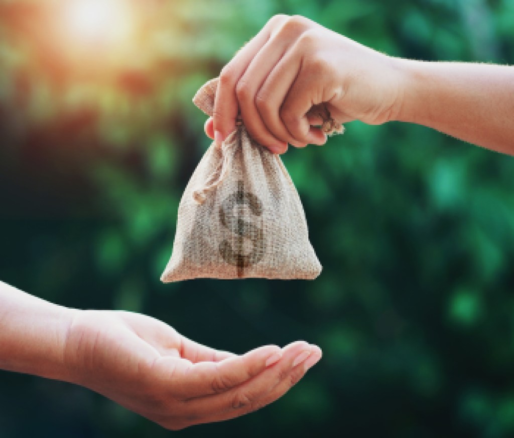 hand giving money bag to another people on green background with sunrise