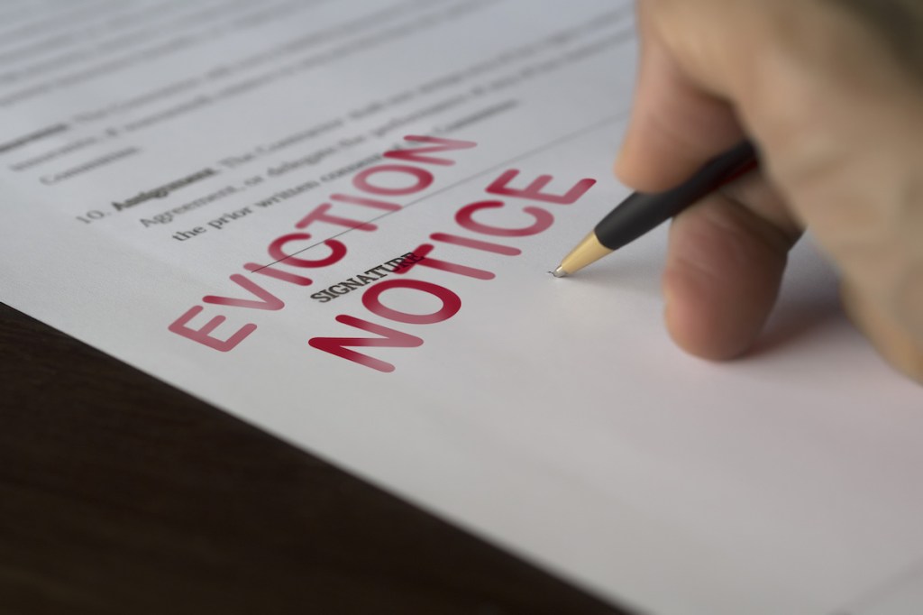 Man signing signing an eviction notice to a defaulting renter in due to missed rent in recession