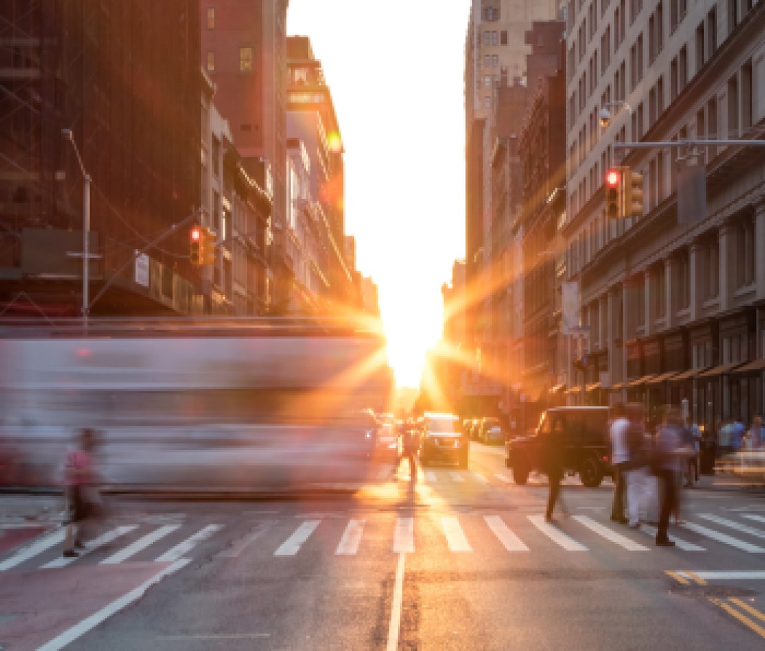 Busy New York City street scene with crowds of people in Midtown Manhattan with sunset background