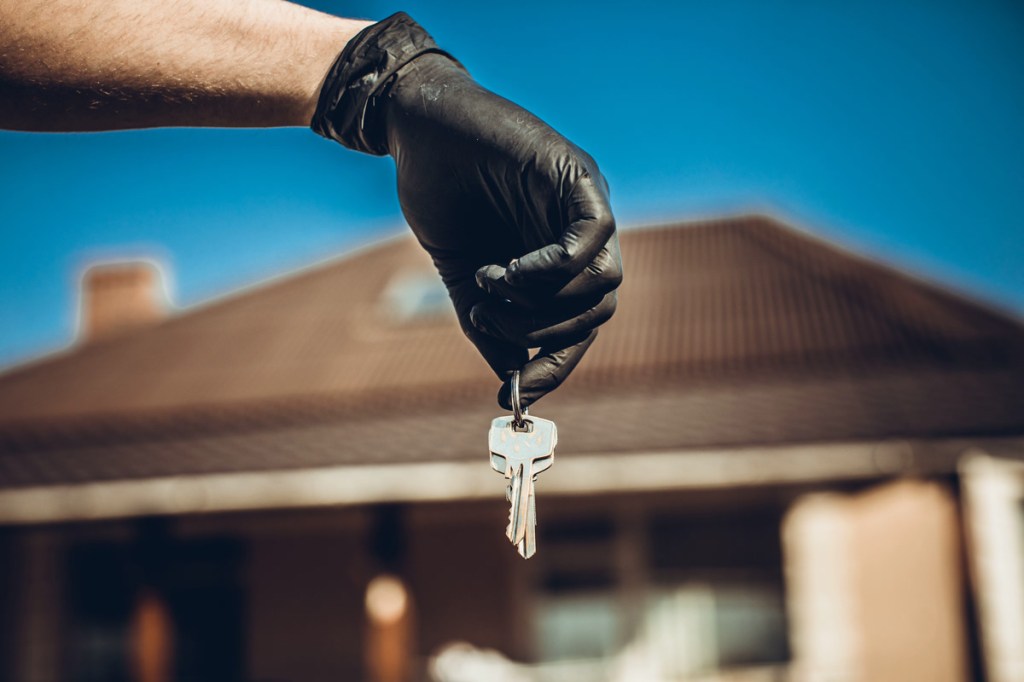 Keys in hand in black glove. Use alcohol spray to corona virus and kill germs at the key of the house or office regularly. Covid-19 ncov or coronavirus quarantine concept.