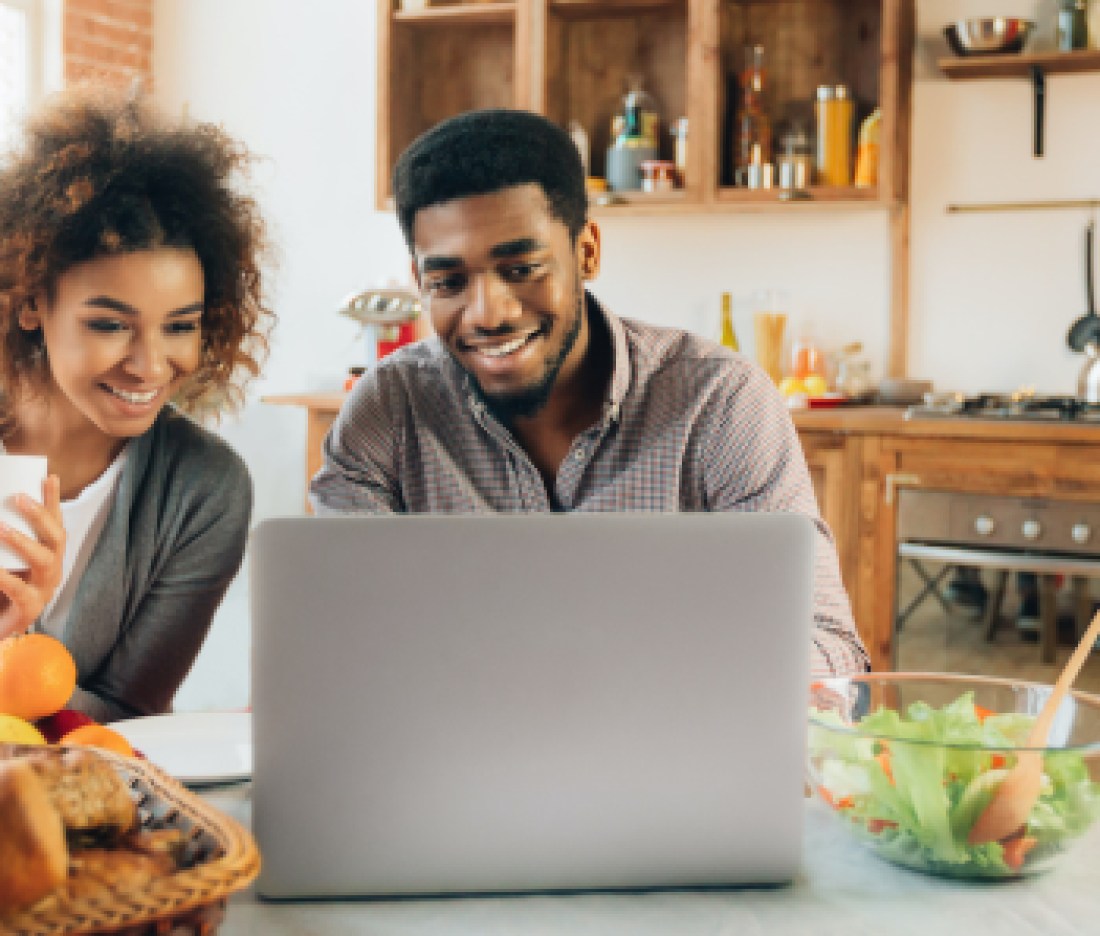 African-american man working on laptop in kitchen