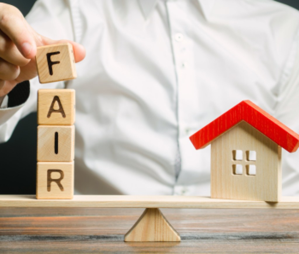 Wooden blocks with the word Fair and a wooden house. Fair value of real estate and housing. Property valuation. Home appraisal. Housing evaluator. Legal transparent deal. Apartment purchase / sale.