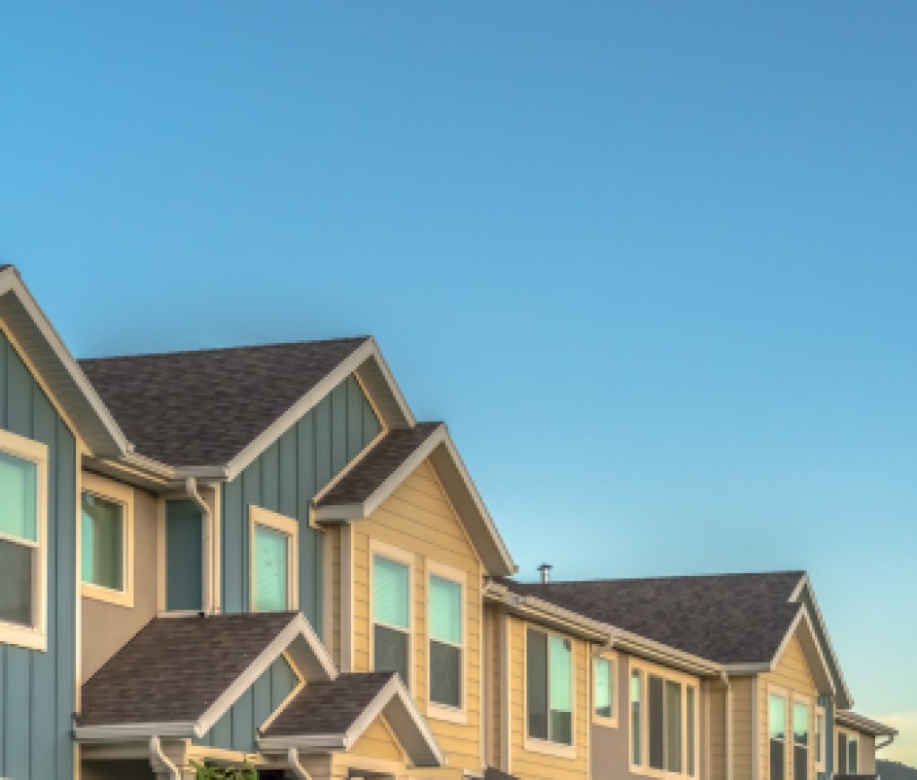 Exterior of upper storey of townhomes with blue sky background on a sunny day