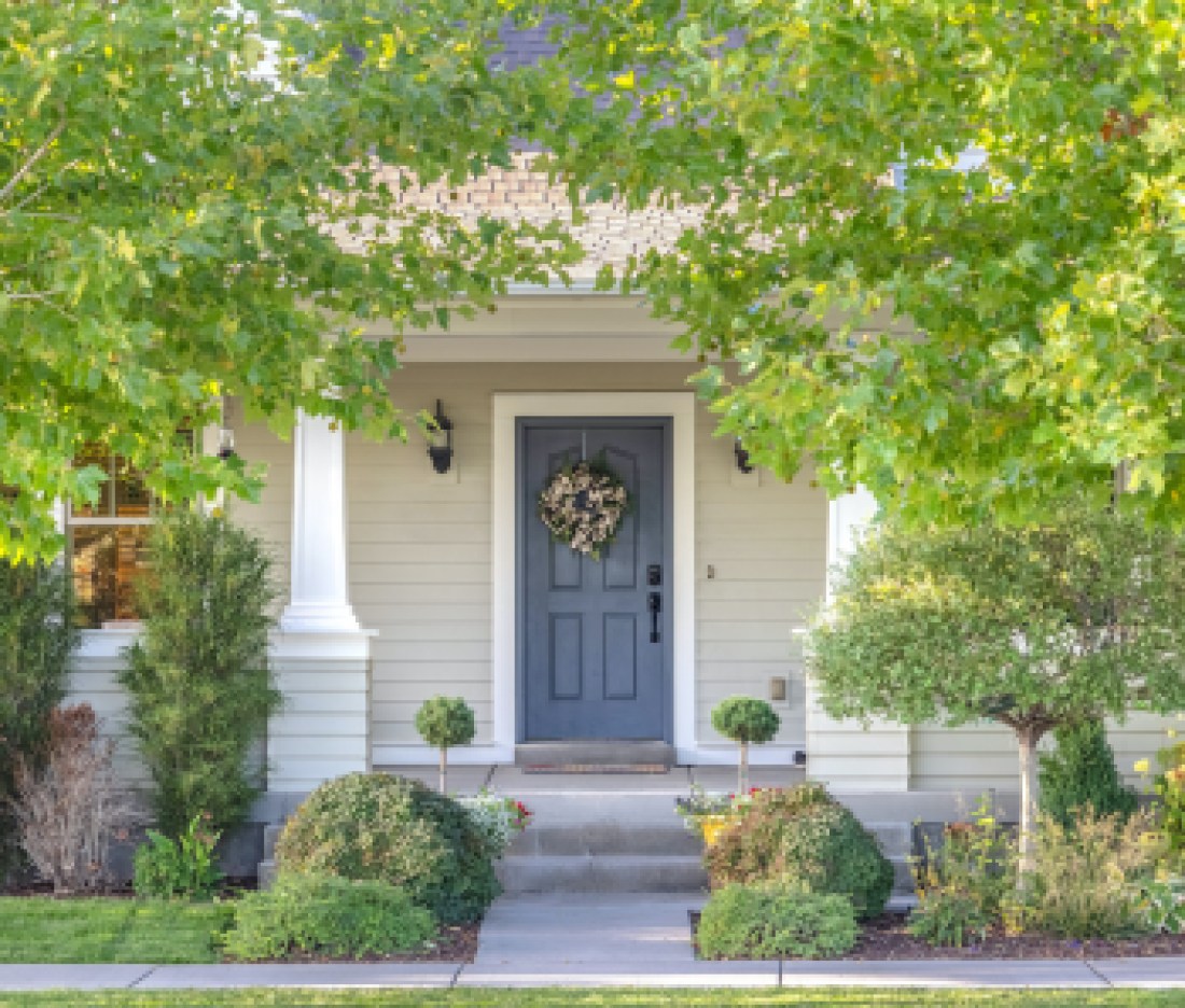Front door of a home surrounded by leafy trees