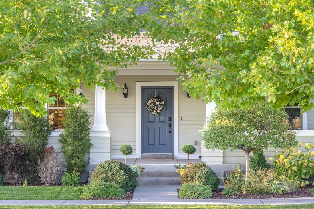 Front door of a home surrounded by leafy trees