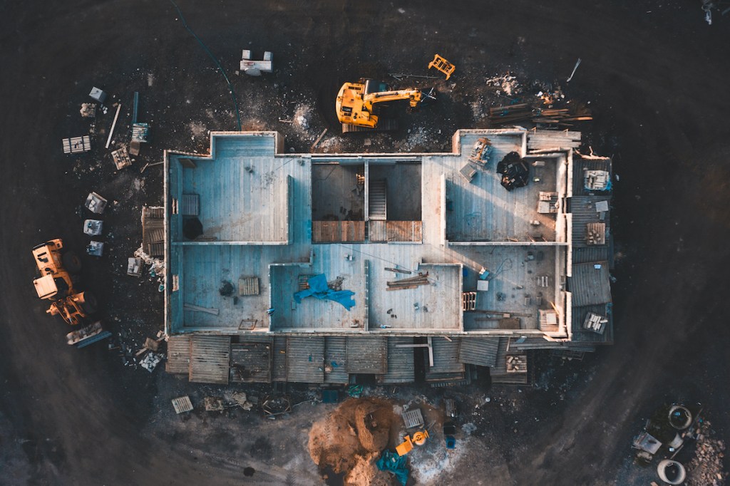 Aerial birds eye image of the frame of a house being built on a construction site at sunset - Wooden floor and walls are visible