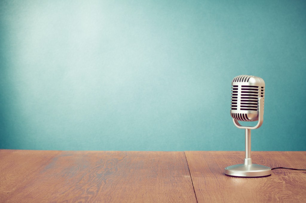 Retro style microphone on table in front aquamarine wall