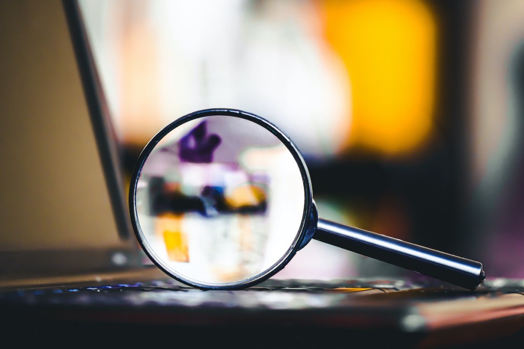 Magnifying glass on laptop keyboard. Internet security concept background.