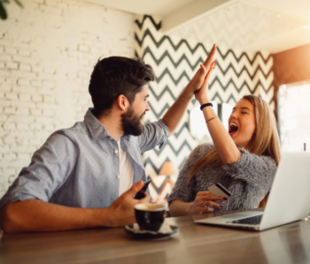 Portrait of an excited young couple giving high five while shopping online.