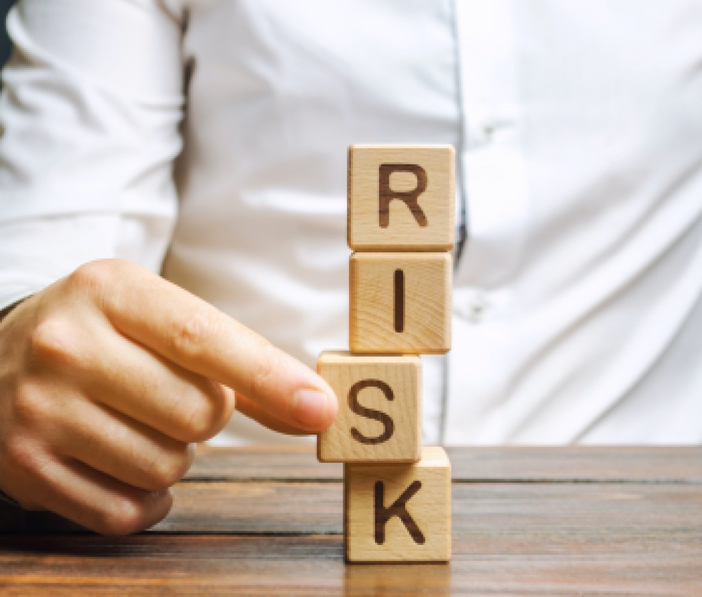 Man removes blocks with the word Risk. The concept of reducing possible risks. Insurance, stability support. Legal protection of business interests. Favorable investment climate. Financial pillow.