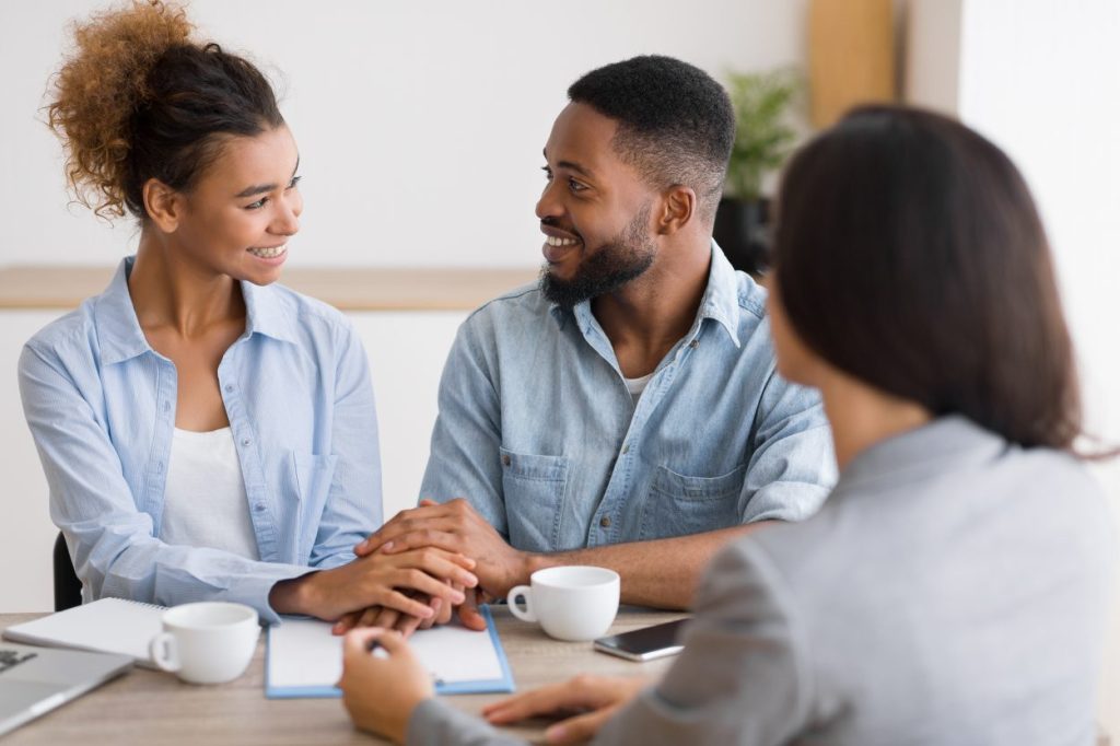 Smiling african american couple holding hands in financial advisor's office