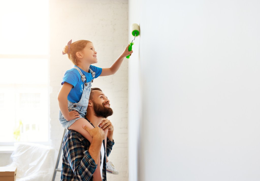 Repair in apartment. Happy family father and child daughter paints wall