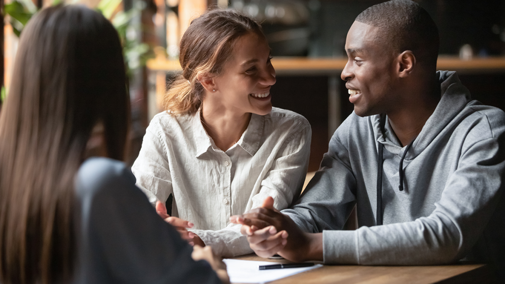 Young couple reviewing house hunting checklist with real estate agent